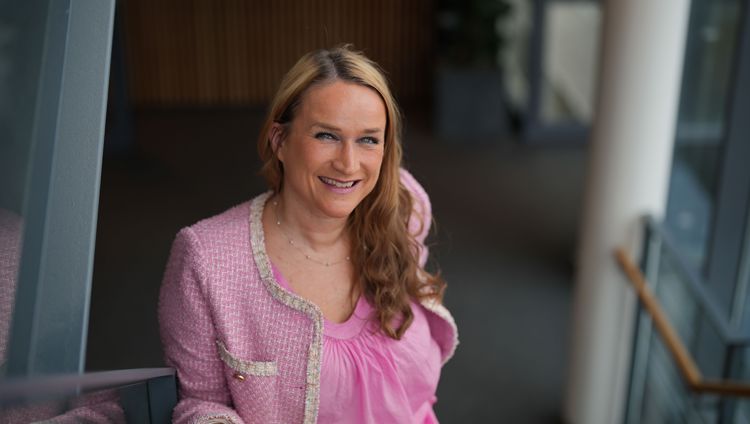 Kvinne med langt hår som smiler og ser inn i kamera