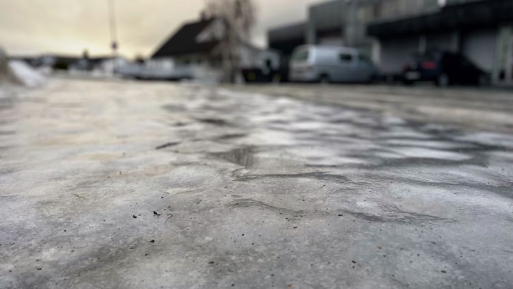 Bildet viser en islagt bakke som delvis er strødd med strøsand.