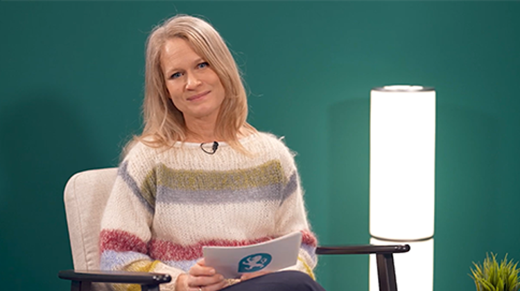 Bildet viser en kvinne som sitter i en stol i et studio og snakker 